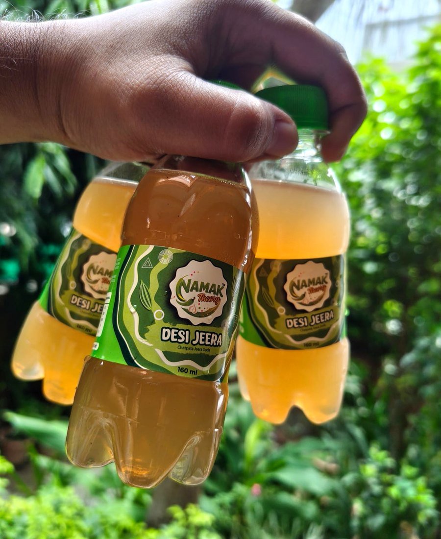 Hand holding NAMAK Theory Desi Jeera bottles
